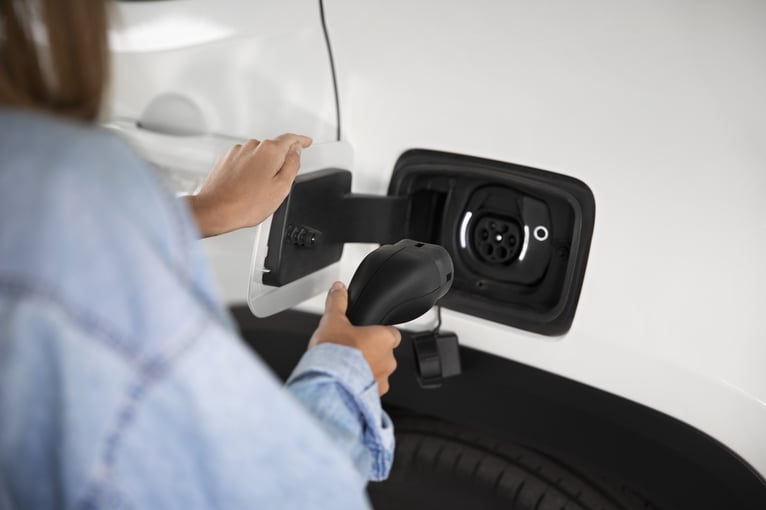 Una persona utiliza un cargador para cargar su coche eléctrico 